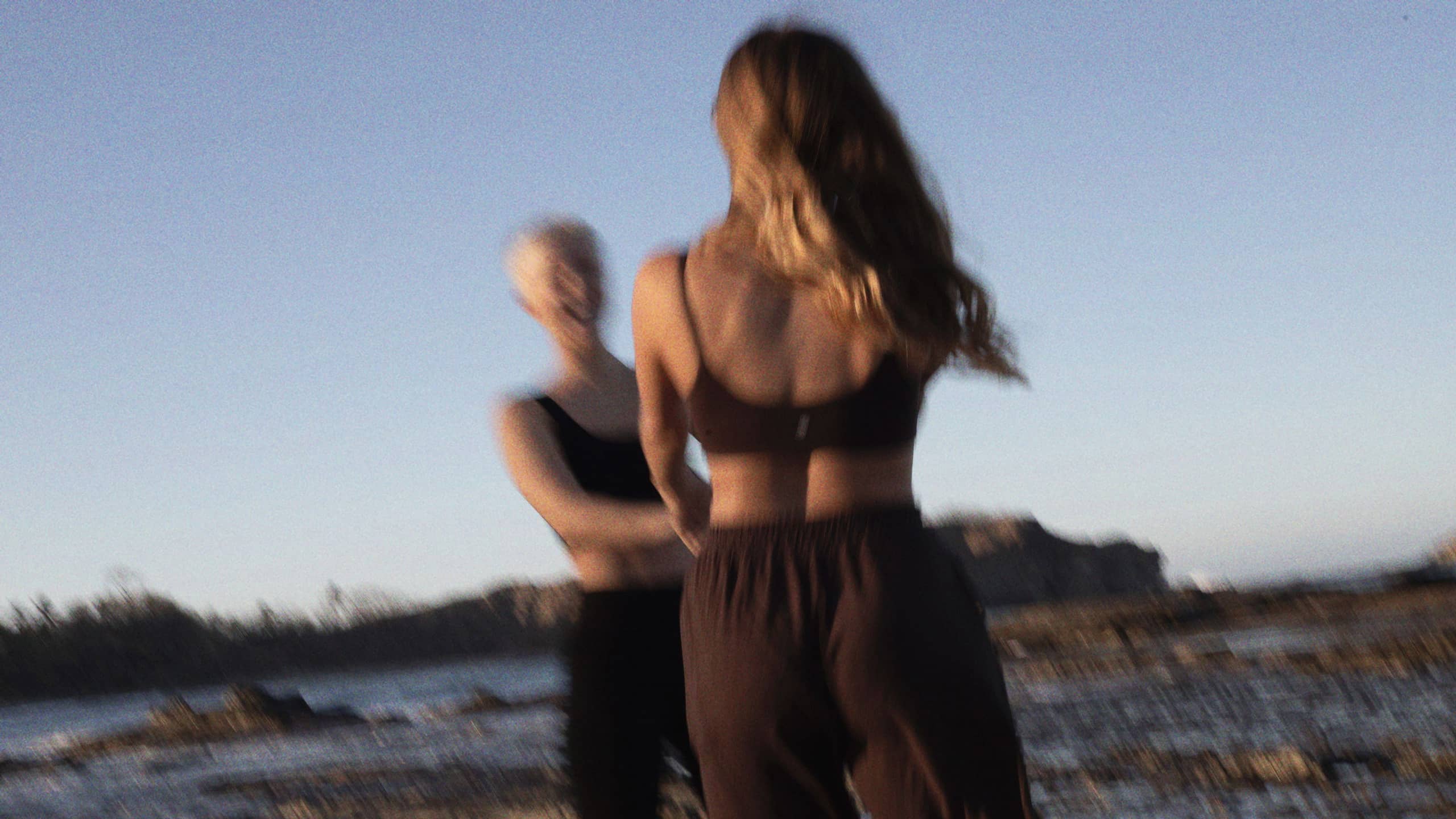 Charlotte and Katja dancing on the beach at dusk